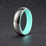 Luminescent Luxe sterling silver 5 mm ring with Aqua Glow liner, glowing softly in dim light, on a subtly cooler gray background.