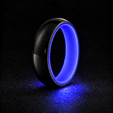 Luminescent Luxe sterling silver 5 mm ring with Indigo liner, glowing powerfully in deep darkness, on a subtly cooler gray background.