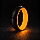 Luminescent Luxe sterling silver 5 mm ring with Racing Orange liner, glowing powerfully in deep darkness, on a subtly cooler gray background.