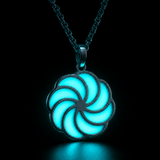 Sterling silver luminous spiral pendant glowing aqua in dark lighting