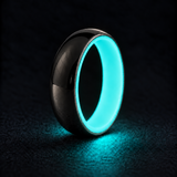 Luminescent Luxe sterling silver 5 mm ring with Aqua Glow liner, glowing powerfully in deep darkness, on a subtly cooler gray background.