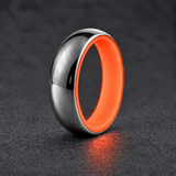 Luminescent Luxe sterling silver 5 mm ring with Fire Glow liner, glowing softly in dim light, on a subtly cooler gray background.
