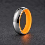 Luminescent Luxe sterling silver 5 mm ring with Racing Orange liner, glowing softly in dim light, on a subtly cooler gray background.