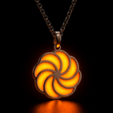Sterling silver luminous spiral pendant glowing yellow-orange in dark lighting